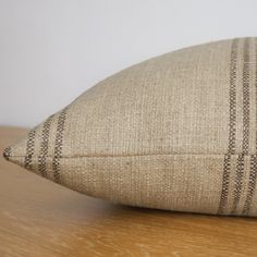 a brown and white striped pillow sitting on top of a wooden table