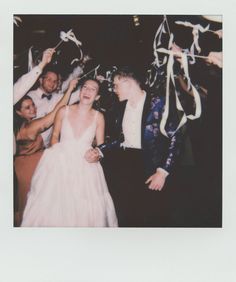 a group of people standing next to each other at a party with streamers in the air