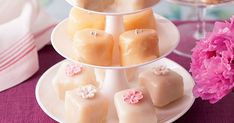 three tiered trays filled with different types of cakes and pastries next to pink flowers