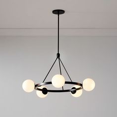 a black chandelier with five white balls hanging from it's center point