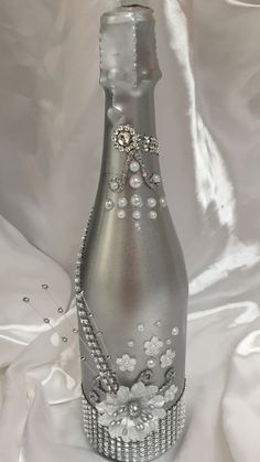 a bottle that is sitting on a white cloth with pearls and beads around it's neck