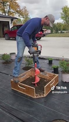 a man is using a power drill to plant some plants in the ground on top of a deck