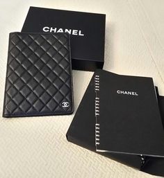 three black chanel wallets sitting next to each other on top of a bed