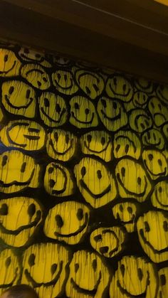 a bunch of smiley faces drawn on a piece of wood that has been painted yellow