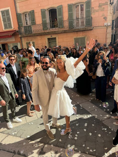 a bride and groom walking through confetti on the street in front of a crowd