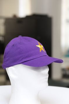 a white mannequin head wearing a purple hat with a yellow star on it