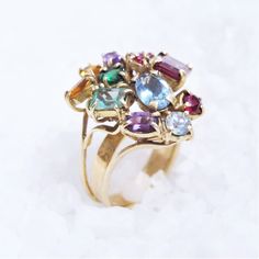 Floral ring with multiple stones. Ring composed of gems of different colors, varieties and sizes. _ Burgundy emerald cut is garnet (2,5ct) _ Emerald cut green and emerald (0,45ct) _ Oval cut in light blue is aquamarine (1,2ct) _ Purple oval cut is amethyst (0.3ct) _ Yellow oval cut is citrine (0,3ct) _ Round cut green is tsavorite (0.35ct) _ Round cut light blue is aquamarine (0,30ct) _ Round cut pink and garnet (0,35ct) _ Round cut red is ruby (0, 20ct) Total weight is 8 grams The ring has a ro Elegant Green Multi-stone Topaz Ring, Multicolor Multi-stone Birthstone Ring Fine Jewelry, Multicolor Gemstone Birthstone Ring For Wedding, Elegant Multicolor Multi-stone Birthstone Ring, Heirloom Multicolor Gemstone Ring, Oval Multi-stone Emerald Gemstones, Multicolor Oval Amethyst Ring With Gemstone Accents, Yellow Gold Multi-stone Ruby Ring, Multicolor Oval Multi-stone Cluster Ring