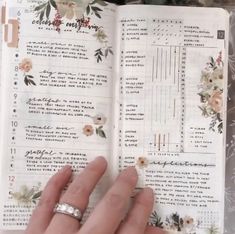 someone is holding their wedding ring in front of an open book with flowers on it