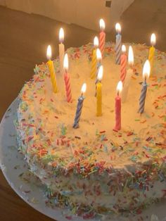 a birthday cake with many lit candles on it's icing and sprinkles