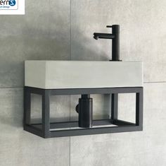 a black and white sink mounted to the side of a wall with a soap dispenser