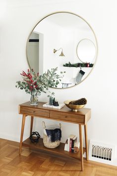 a wooden table topped with a mirror next to a vase filled with flowers and plants