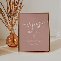 a pink sign sitting on top of a table next to a vase filled with dry grass