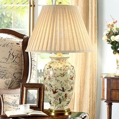 a lamp sitting on top of a table next to a vase with flowers in it