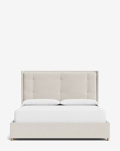 a bed with white sheets and pillows in front of a gray wall, it's headboard is upholstered