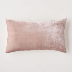 a pink velvet pillow on a white wall with a light brown border around the edges