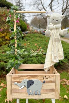 a wooden box with an elephant on it and a stuffed animal hanging from the top