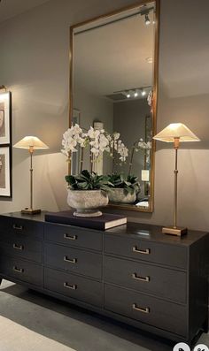 a large mirror sitting on top of a dresser next to a vase filled with flowers