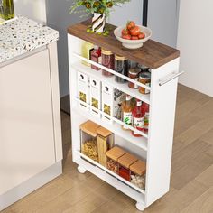 a white kitchen cart with spices and condiments on the top, next to a bowl of fruit