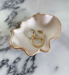 two gold wedding rings in a shell shaped dish