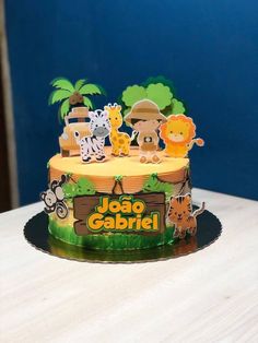 a birthday cake with animals and trees on it's top is sitting on a table