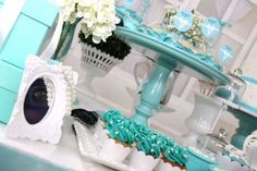 a table topped with cupcakes covered in frosting and blue icing next to vases filled with white flowers