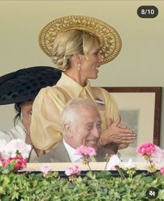 two women and an older man are looking at each other while standing in front of flowers