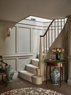 a room with stairs and vases on the table in front of it, along with other furniture