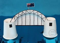 two white cups sitting on top of a blue table next to a fence and flag