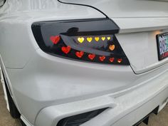 the rear end of a white car with hearts on it's tail lights and license plate