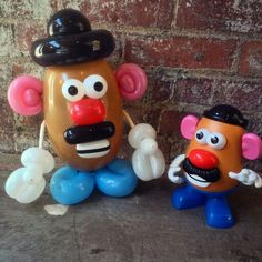 two inflatable toys are standing next to each other near a brick wall,