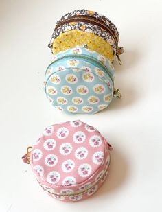 four coin purses are lined up on a white surface, one is pink and the other is blue