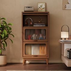 a wooden cabinet sitting next to a potted plant on top of a hard wood floor