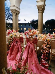 two chairs covered in pink cloths sit next to each other near flowers and candles