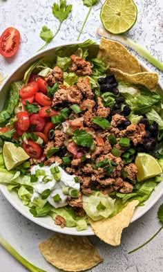 a salad with lettuce, tomatoes, black beans and tortilla chips