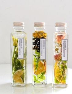 three bottles filled with different types of flowers and herbs