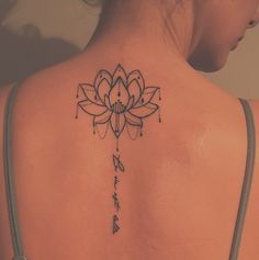 the back of a woman's shoulder with a lotus tattoo on her upper arm