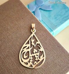 a pendant with an arabic calligraphy in the middle on top of a brown book