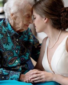 an older woman sitting next to a younger woman with her hands on her chest, both looking at each other