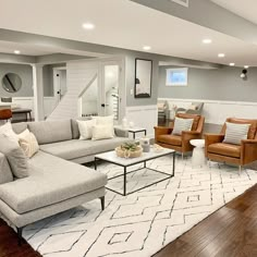 a living room with couches, chairs and a white rug on the wooden floor