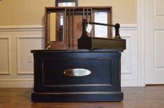 an old fashioned clock sitting on top of a black cabinet in a room with white walls