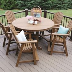 a table and chairs on a deck with trees in the background