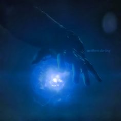 two hands reaching out towards each other in front of a blue light that is shining