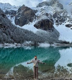 a man standing in front of a mountain lake