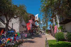 a street lined with shops and trees on both sides of the road is covered in american flags