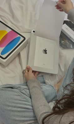 a woman is sitting on the bed with an apple ipad in her lap and holding it up