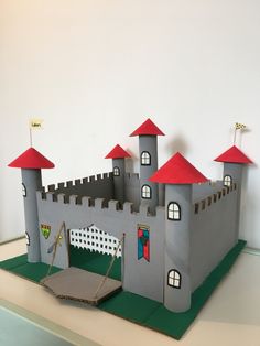 a castle made out of paper on top of a green surface with red roof tops