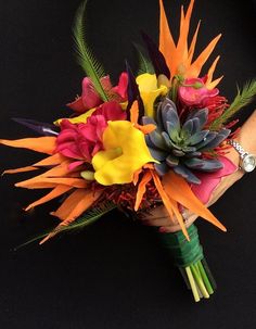 a bridal bouquet made up of flowers and leaves on a black background with a woman's hand holding it