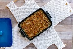 a casserole dish is sitting on a table next to a blue container and spoon