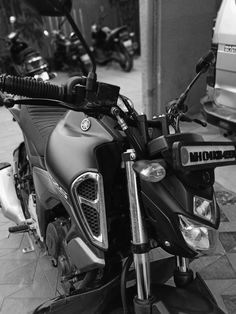 black and white photograph of a motorcycle parked in front of a building with other motorcycles