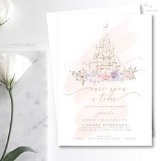 a pink and white wedding card with a castle on the front, surrounded by flowers